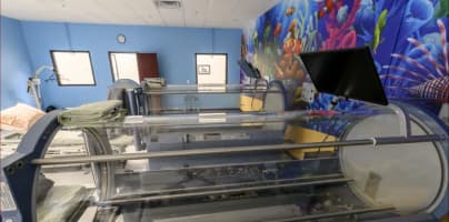 Interior of a medical facility showing a hyperbaric oxygen chamber in a treatment room, with the headline “Fire Safety Tips Target Hyperbaric Oxygen Chambers” and source label “NTD.”